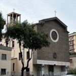 Facciata della chiesa del SS. Sacramento a Tor de' Schiavi, Roma, con campanile, alberi e traffico urbano in primo piano.