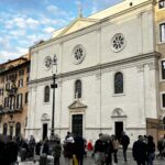 Facciata del Santuario di Nostra Signora del Sacro Cuore a Piazza Navona con persone radunate nella piazza.