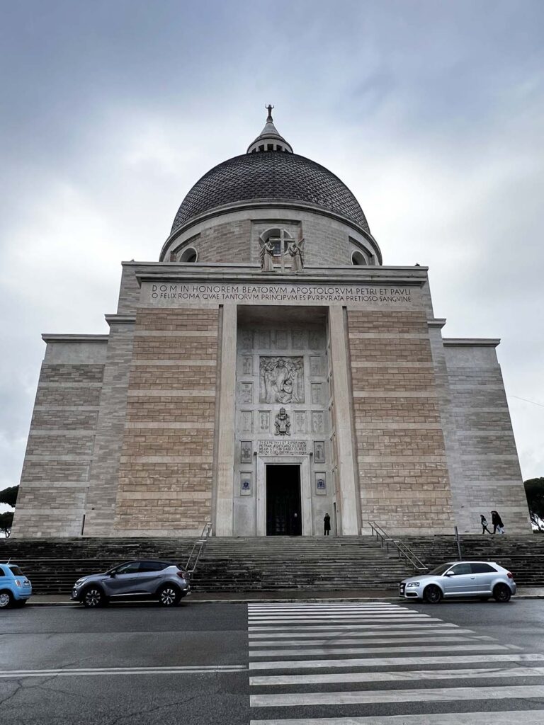 Facciata della Basilica dei Santi Pietro e Paolo all’Eur vista frontalmente in una giornata nuvolosa.