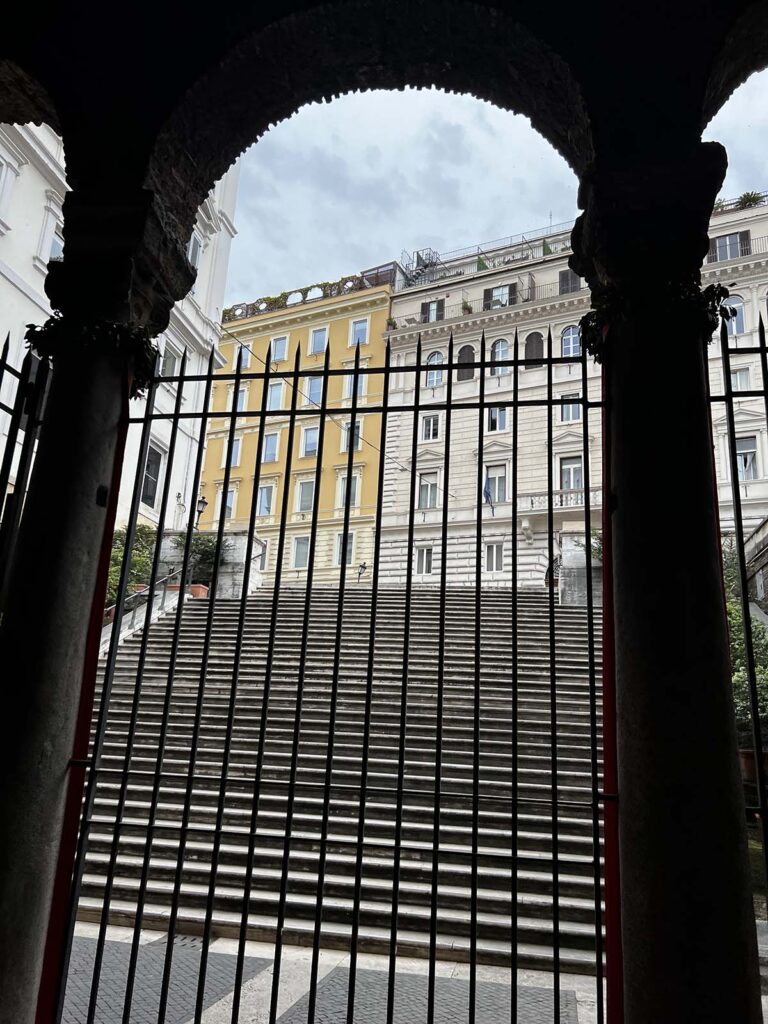 Esterno della chiesa di San Vitale al Quirinale visto dall’interno, con la scalinata che sale verso Via Nazionale e palazzi storici sullo sfondo.